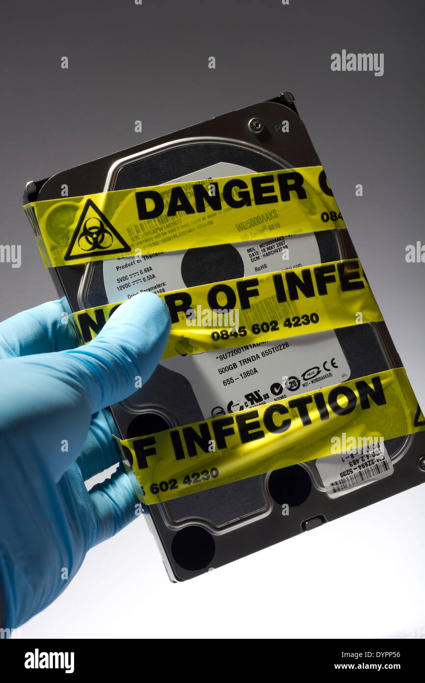 Le latex Gloved Hand Holding Disque dur de l'ordinateur avec du jaune "Danger d'Infection' Bande d'avertissement autour d'elle Banque D'Images