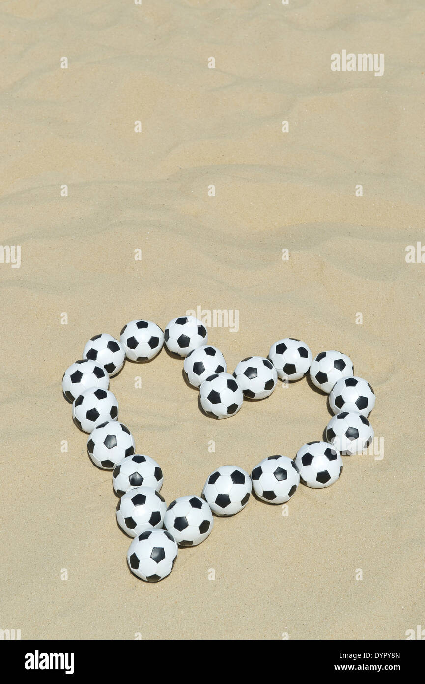 Love Football coeur fait avec des ballons de foot sur plage de sable lumineux de message à Rio de Janeiro Brésil Banque D'Images
