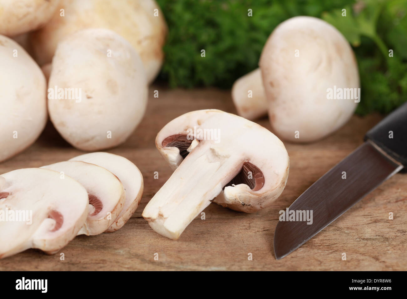 La préparation des aliments : les champignons tranchés avec un couteau sur une carte de cuisine Banque D'Images