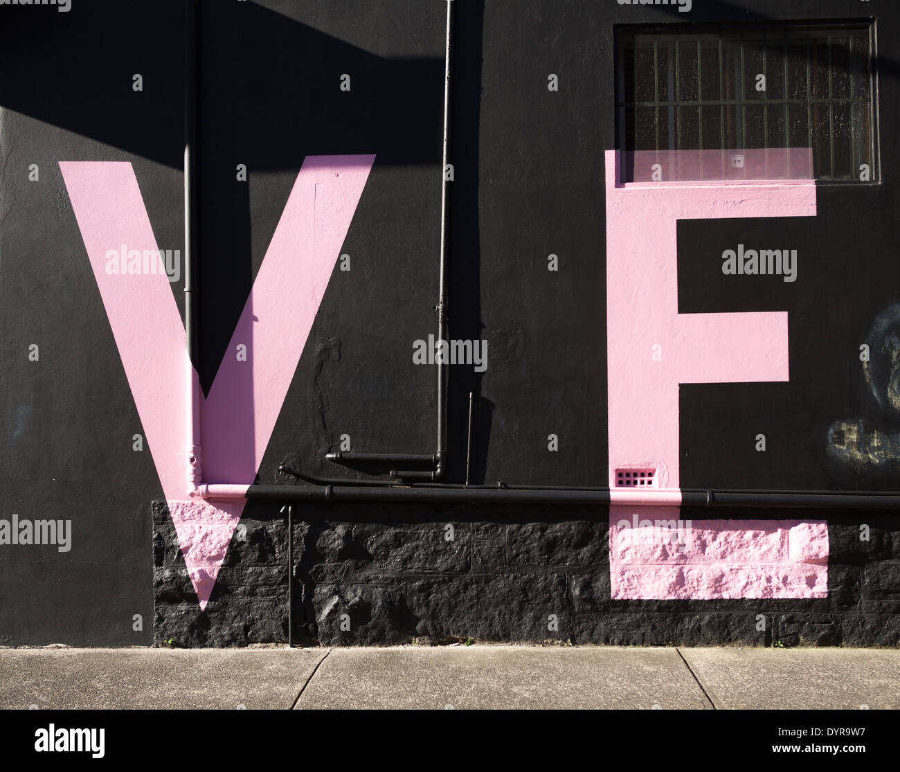 Lettres V et E sur un mur noir écrit en rose Banque D'Images