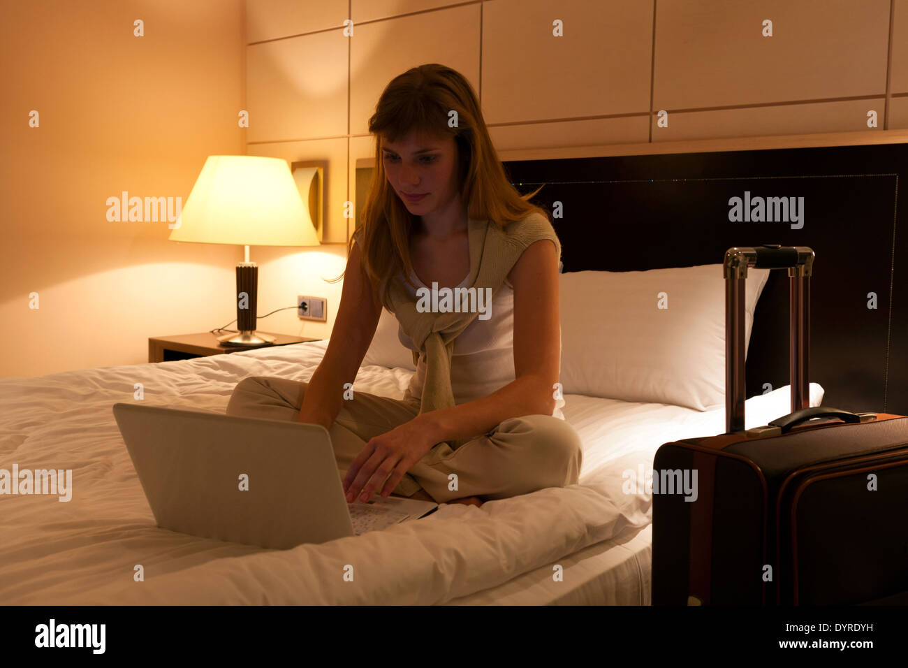 Young woman using laptop dans une chambre d'hôtel Banque D'Images