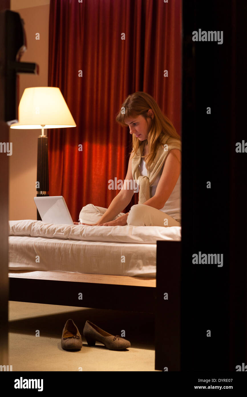 Young woman using laptop dans une chambre d'hôtel Banque D'Images