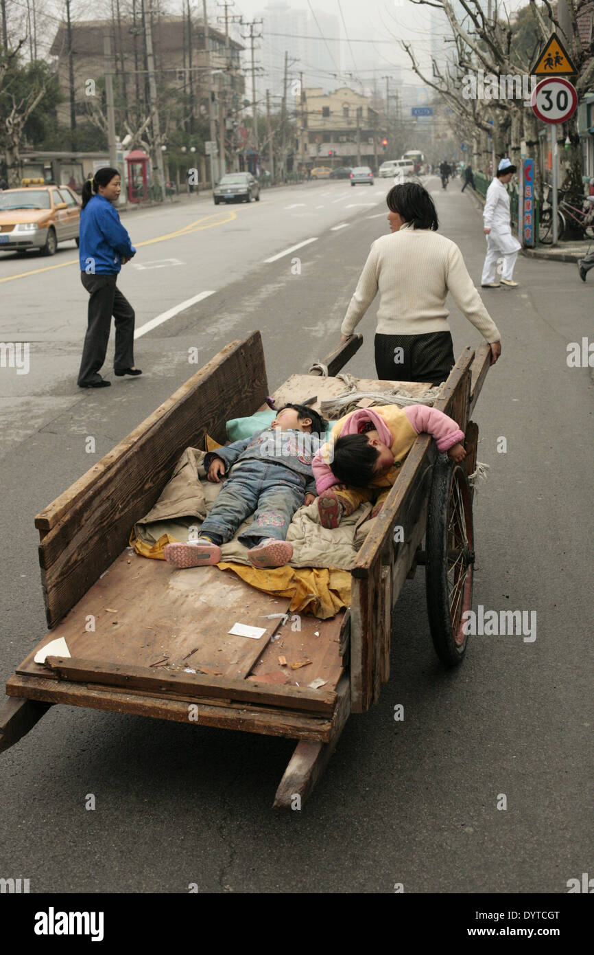 Un travailleur migrant porte son fils sur un chariot sur une route Banque D'Images