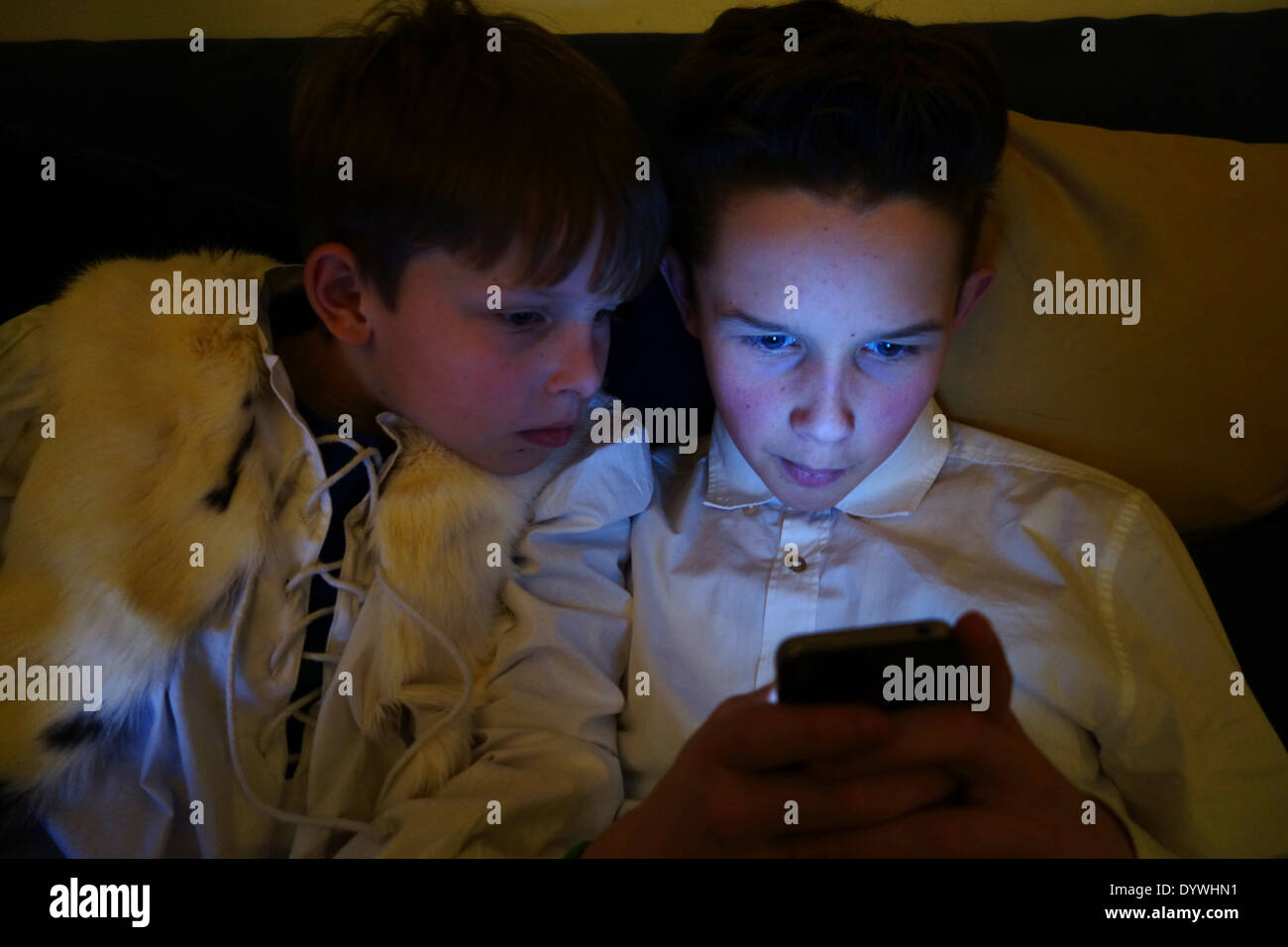 Berlin, Allemagne, deux garçons regarder dans le noir sur un smartphone Banque D'Images