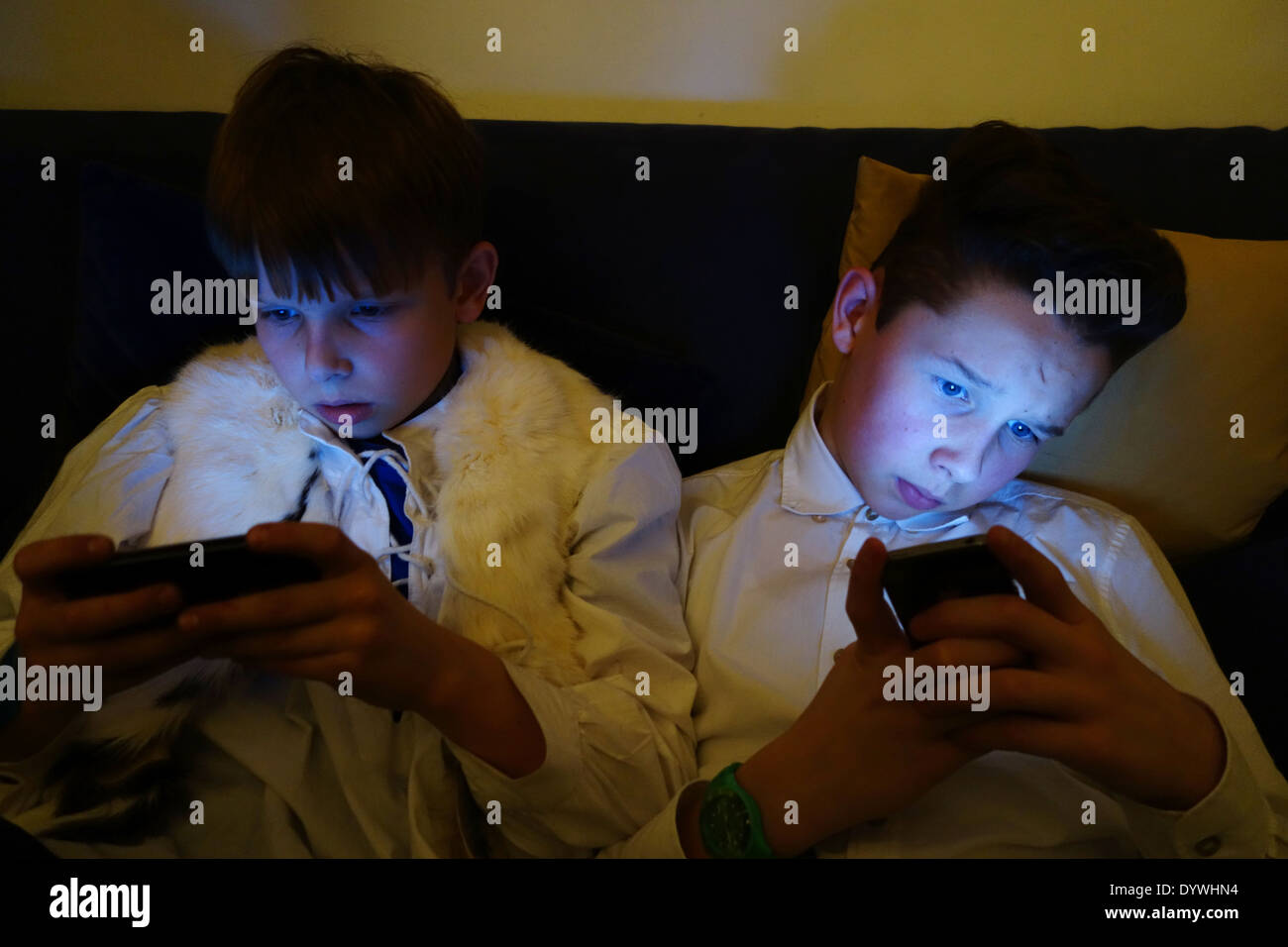 Berlin, Allemagne, deux garçons se regarder dans l'obscurité de leur smartphone Banque D'Images