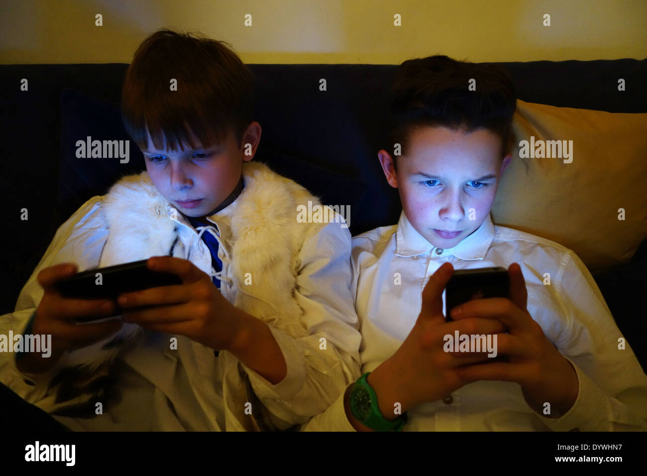 Berlin, Allemagne, deux garçons se regarder dans l'obscurité de leur smartphone Banque D'Images