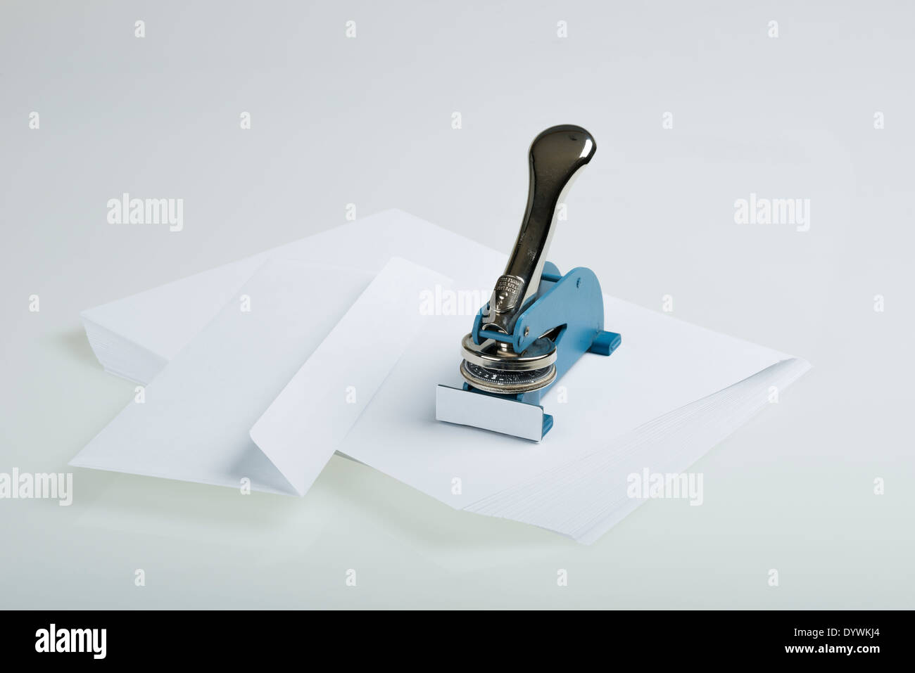 Seal Maker reposant sur une pile de papier blanc à côté d'une enveloppe sur un tableau blanc Banque D'Images