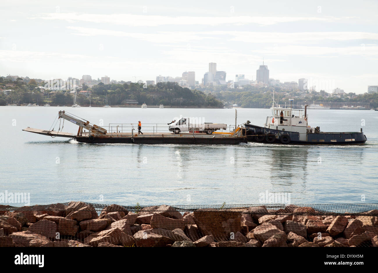 Un remorqueur poussant une barge avec un van sur elle dans le port de Sydney, Australie Banque D'Images