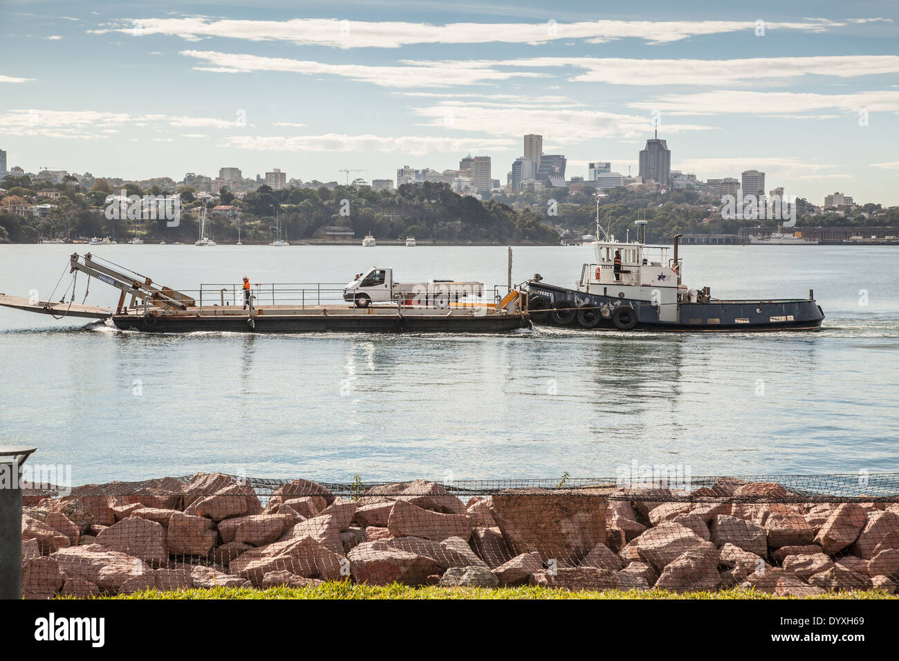 Un remorqueur poussant une barge avec un van sur elle dans le port de Sydney, Australie Banque D'Images