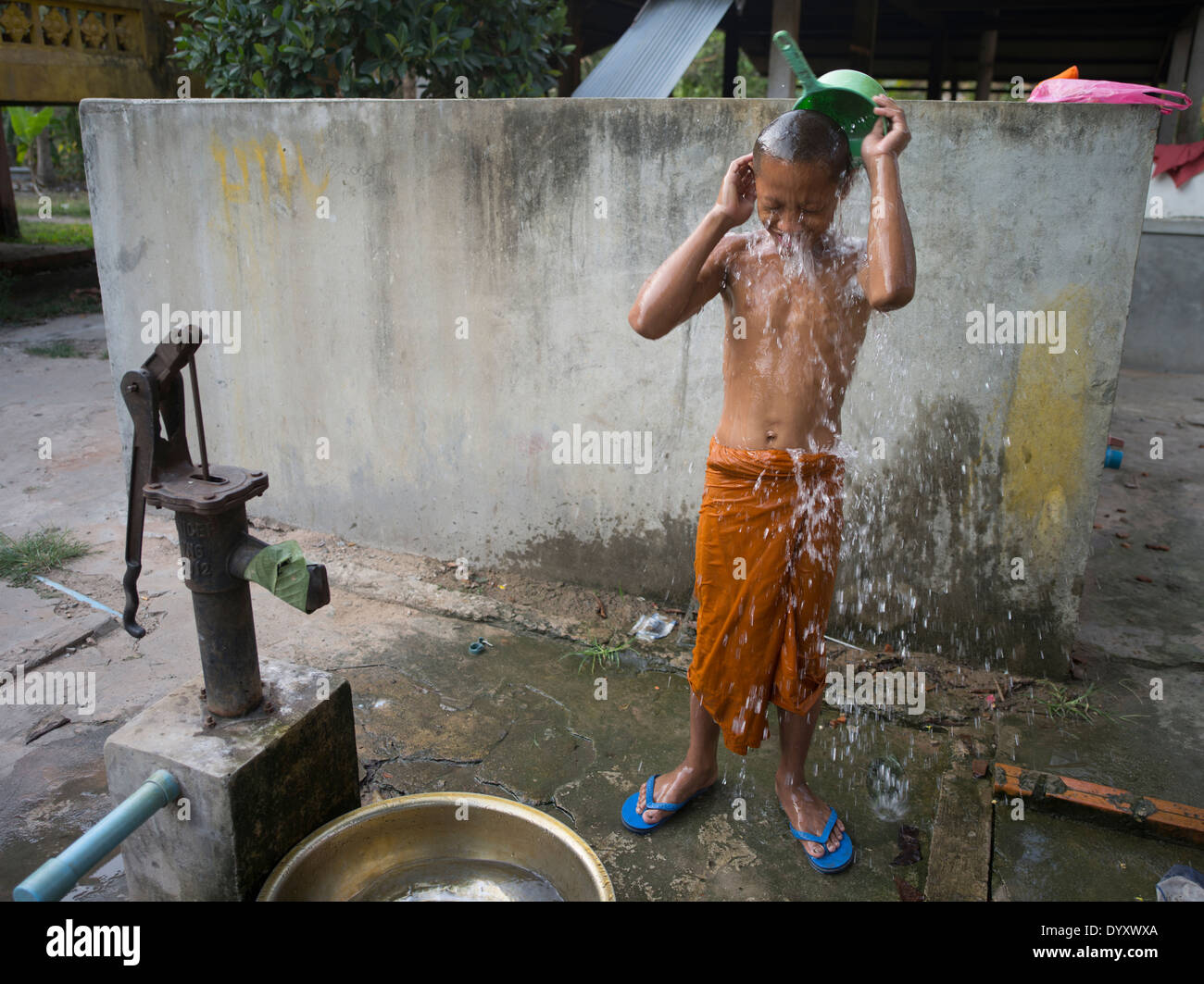 Jeune moine bouddhiste le lavage avec un seau à la pompe à eau. À Angkor Wat, Siem Reap, Cambodge Banque D'Images