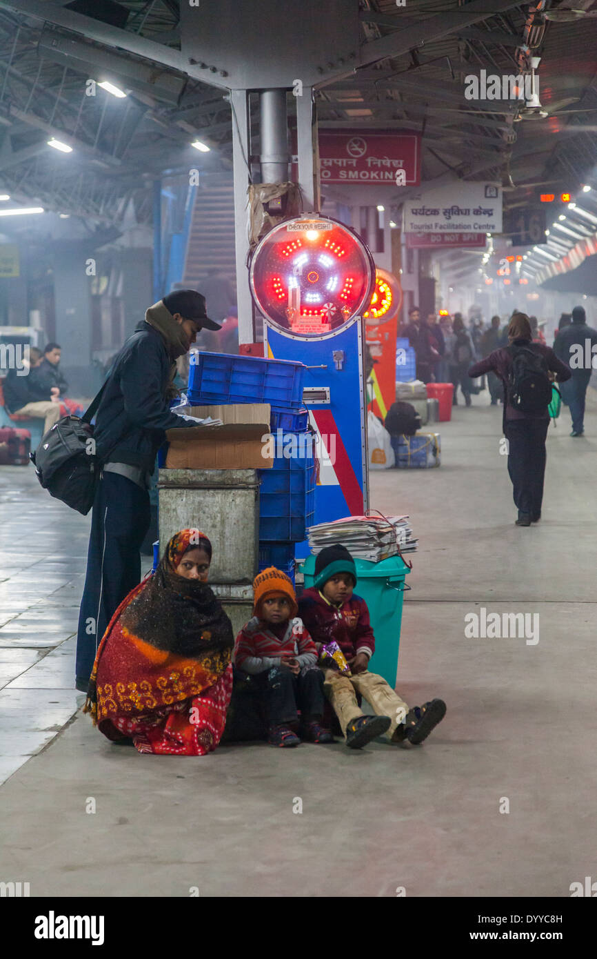 New Delhi, Inde. Mère et enfants en attente de train sur la plate-forme en début de matinée. Banque D'Images