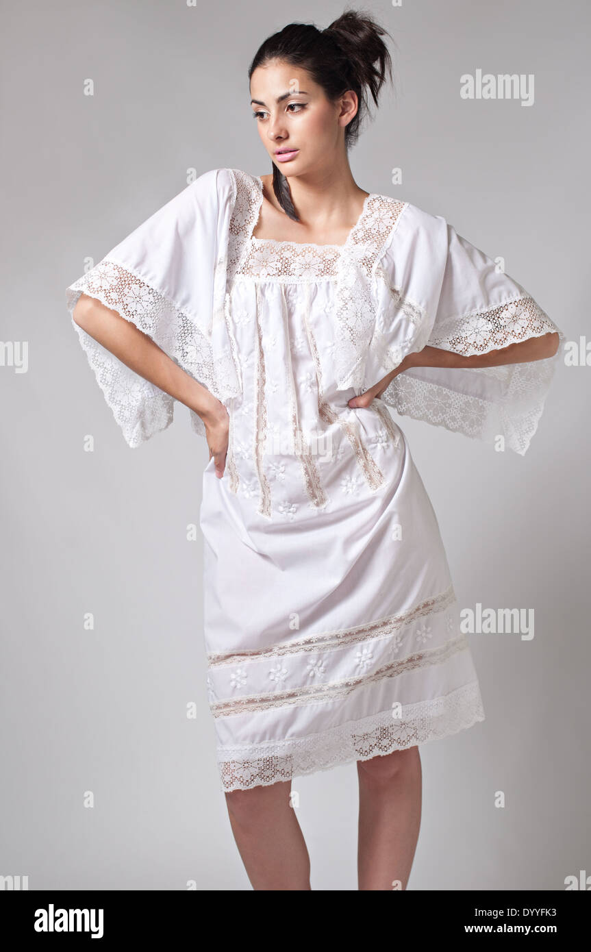 Une femme avec des cheveux noir queue, multiraciale modèle féminin portant un floral romantique 70s white lace dress posing Banque D'Images