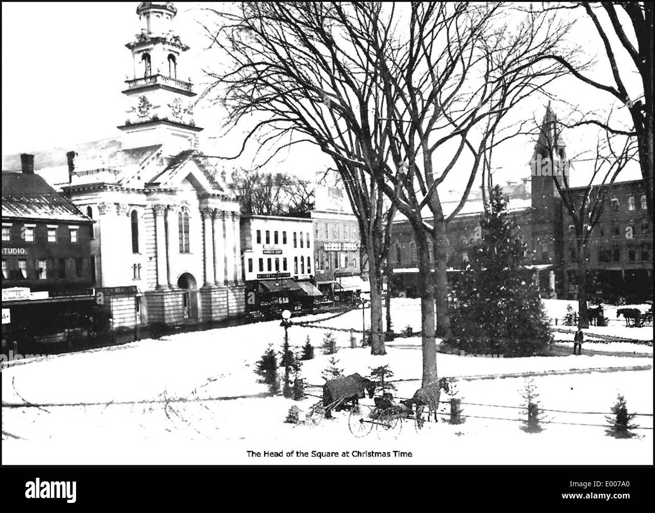 Une scène hivernale représentant Central Square à Keene, New Hampshire, pendant la saison de Noël. La place est ornée de décorations festives et les arbres environnants sont décorés, créant une atmosphère de vacances classique dans le quartier des affaires du centre-ville. Banque D'Images