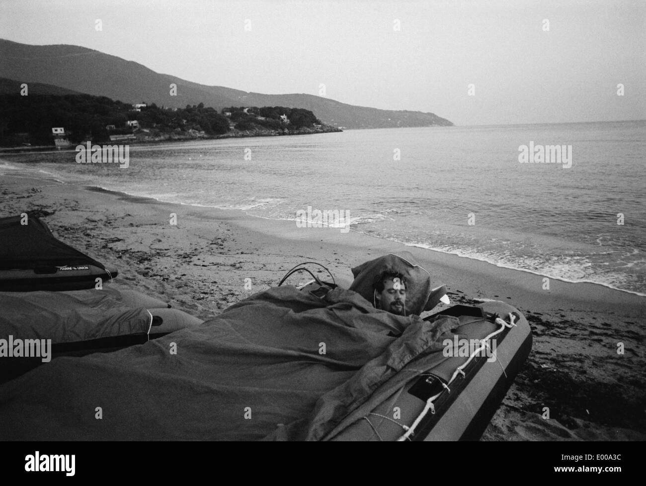 Un homme dormant dans son bateau gonflable sur la côte italienne Banque D'Images