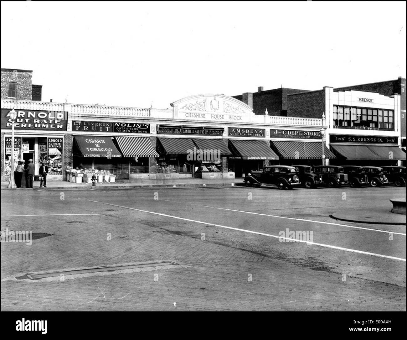 Cette photographie historique montre main Street, sur le côté est de Keene, New Hampshire, au cours des années 1930 L'image capture le quartier des affaires du centre-ville avec ses voitures anciennes, ses bâtiments et ses boutiques, reflétant la vie commerciale de l'époque. Le Cheshire House Block et d'autres éléments architecturaux marquent l'histoire locale de la ville. Banque D'Images