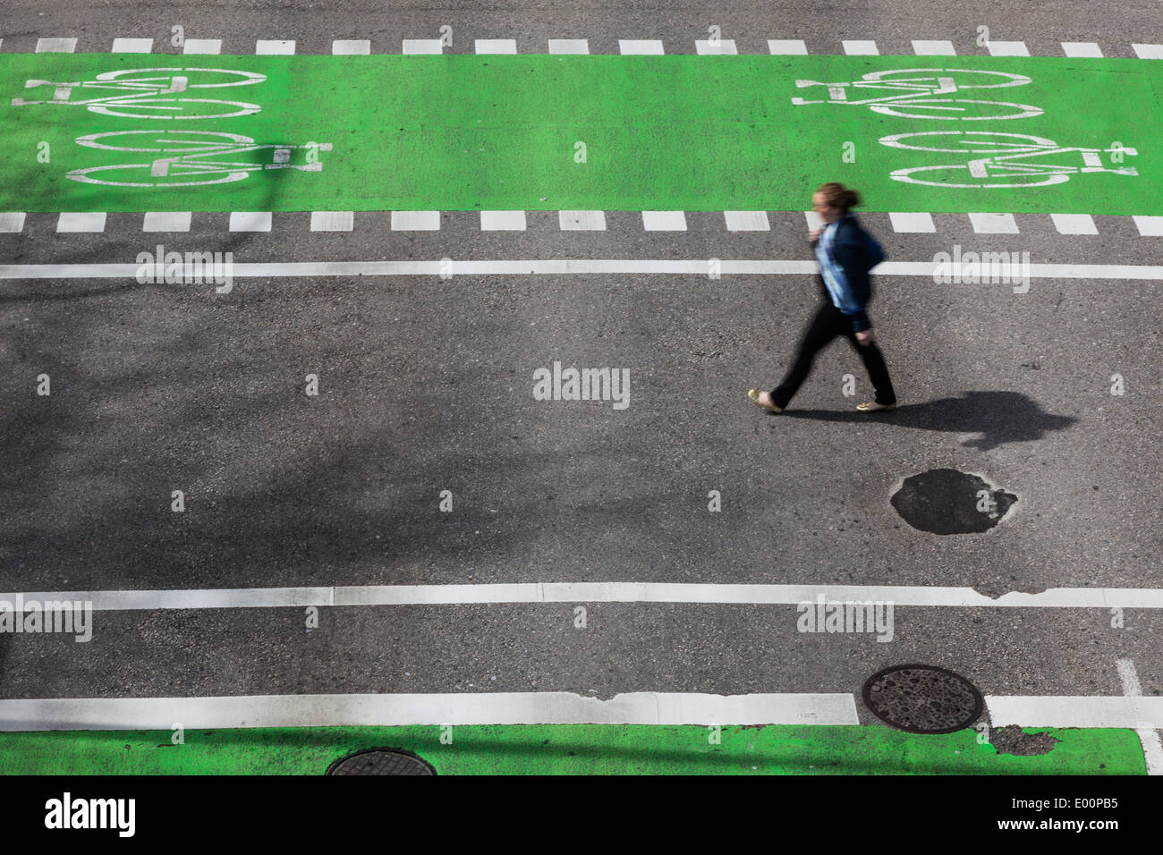 Jeune femme traversant une intersection entre les voies cyclables dédié Banque D'Images