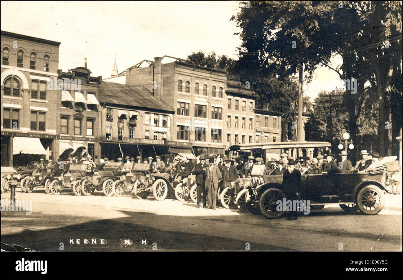 Une vue historique de *Central Square à Keene, NH*, mettant en valeur le quartier des affaires animé de cette ville du New Hampshire. La scène présente des voitures anciennes et des bâtiments typiques du début au milieu du XXe siècle. Banque D'Images