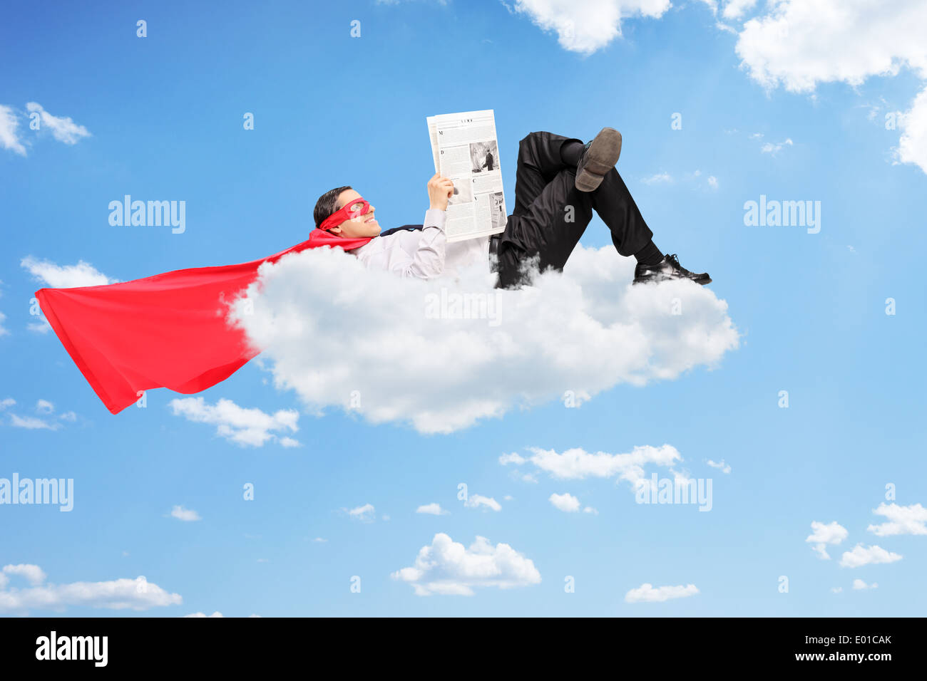 Super-héros masculin allongé sur cloud et lire un journal Banque D'Images