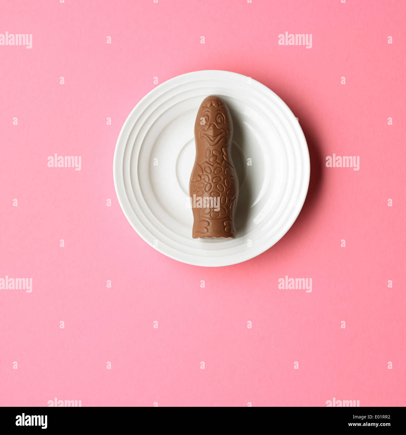 Poulet au chocolat sur une assiette blanche, sur fond rose Banque D'Images