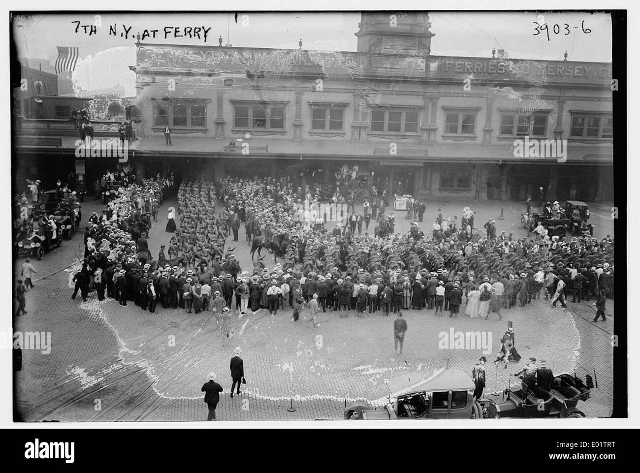 Une image historique du 7th New York Regiment au ferry, capturée à New York. La photographie reflète la présence militaire pendant la période de la guerre de Sécession, avec des soldats en uniforme debout près du terminal de ferry. La scène capture le moment dans le temps avec des drapeaux, des uniformes, et l'atmosphère animée. Banque D'Images