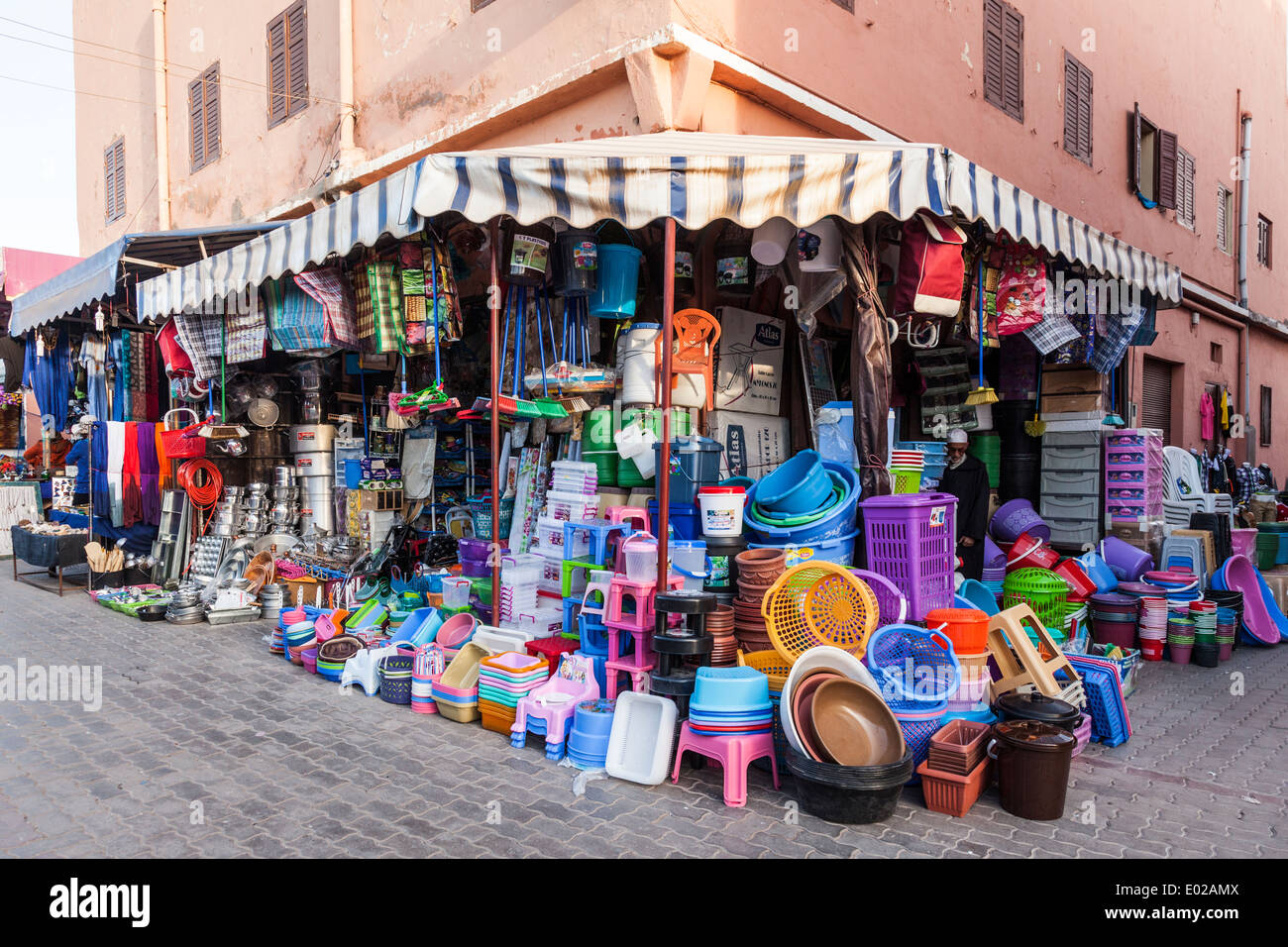 Une boutique qui vend des articles de ménage en plastique lumineux principalement, entre deux magasins de vêtements, dans le centre de Ouazazate, Maroc, Afrique du Nord Banque D'Images