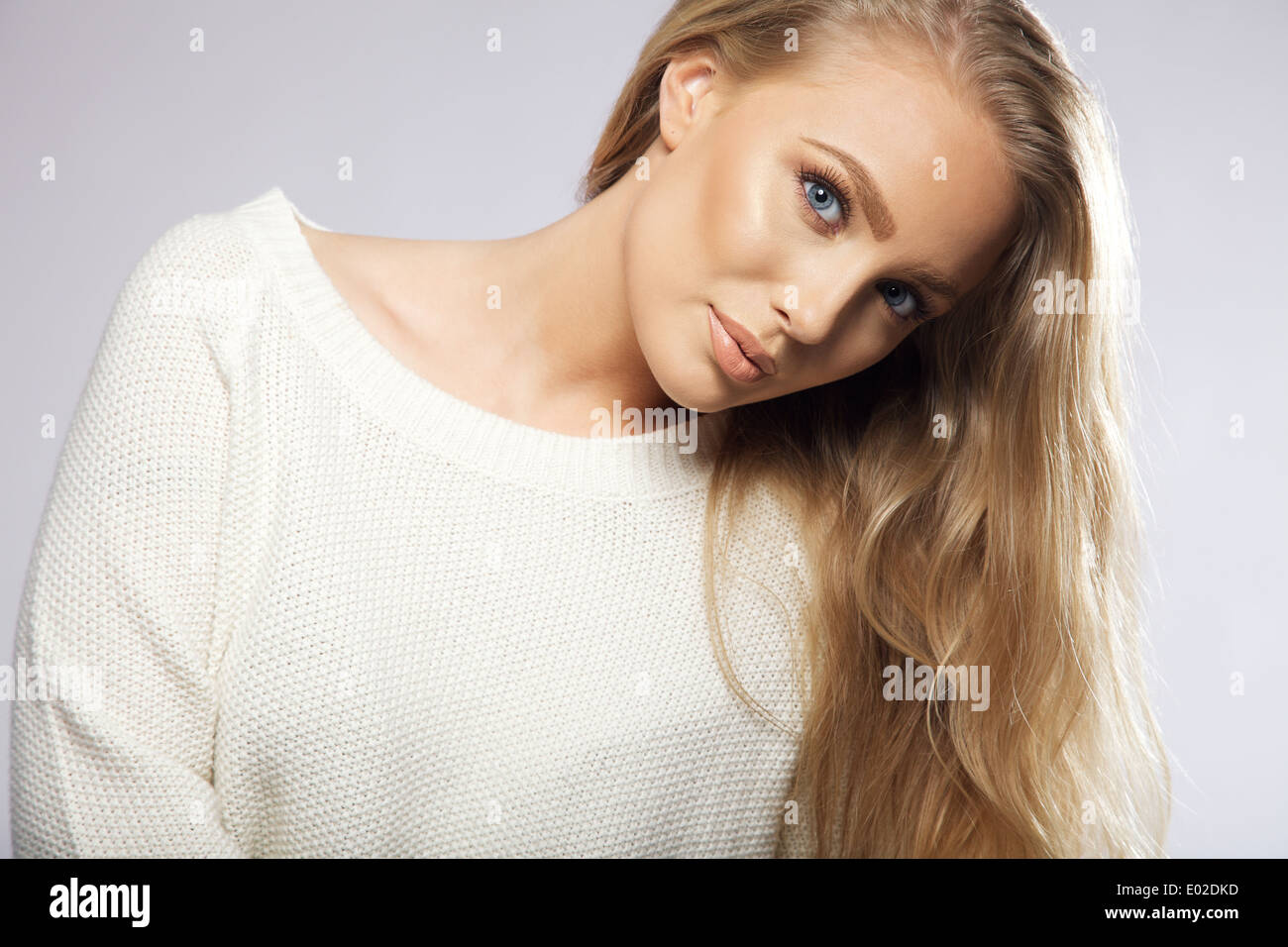 Close up portrait of young woman with long hair looking at camera. belle femme fashion model wearing white sweater. Banque D'Images