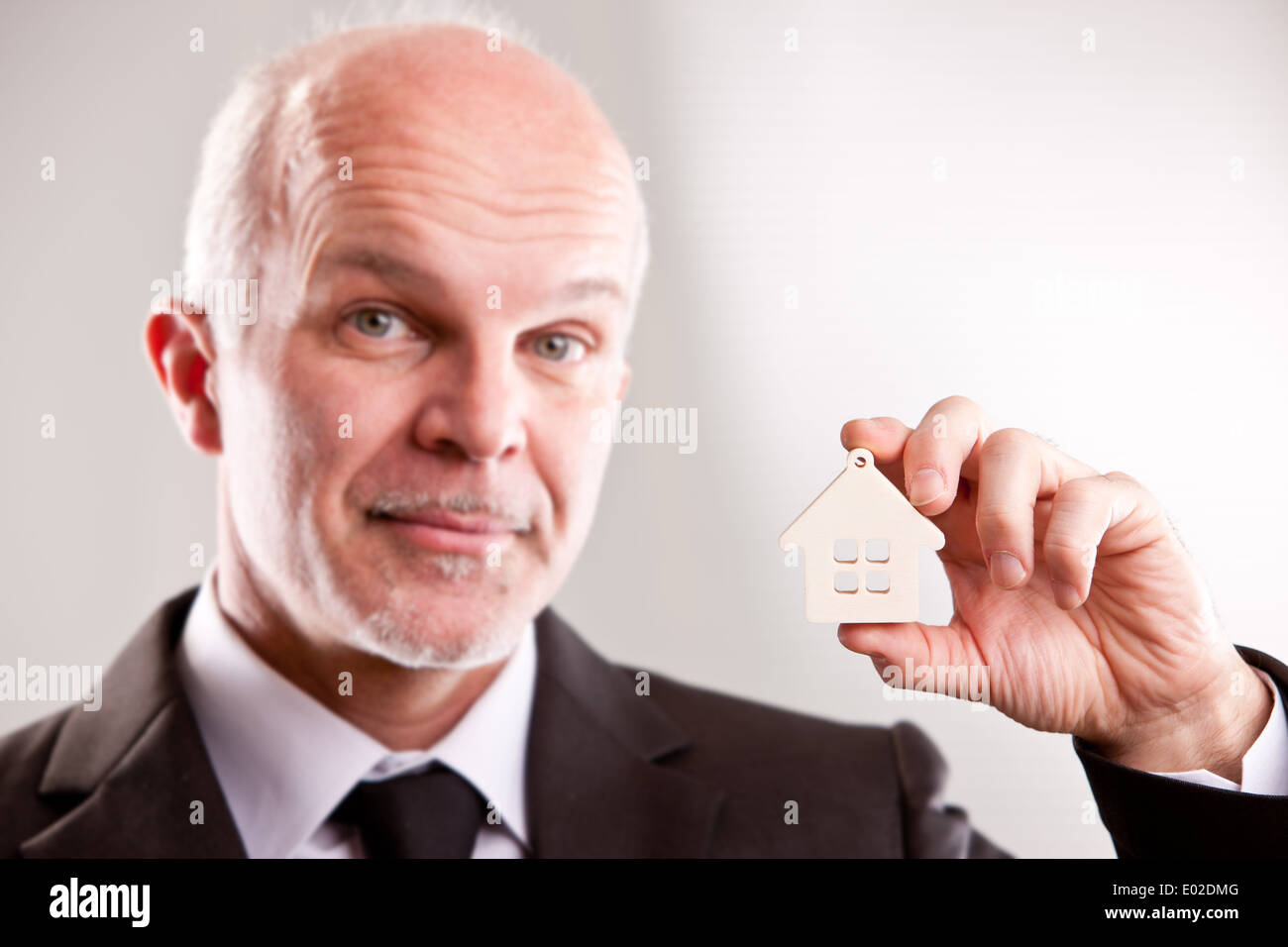 Homme d'âge moyen avec une petite maison dans la main en vous regardant Banque D'Images