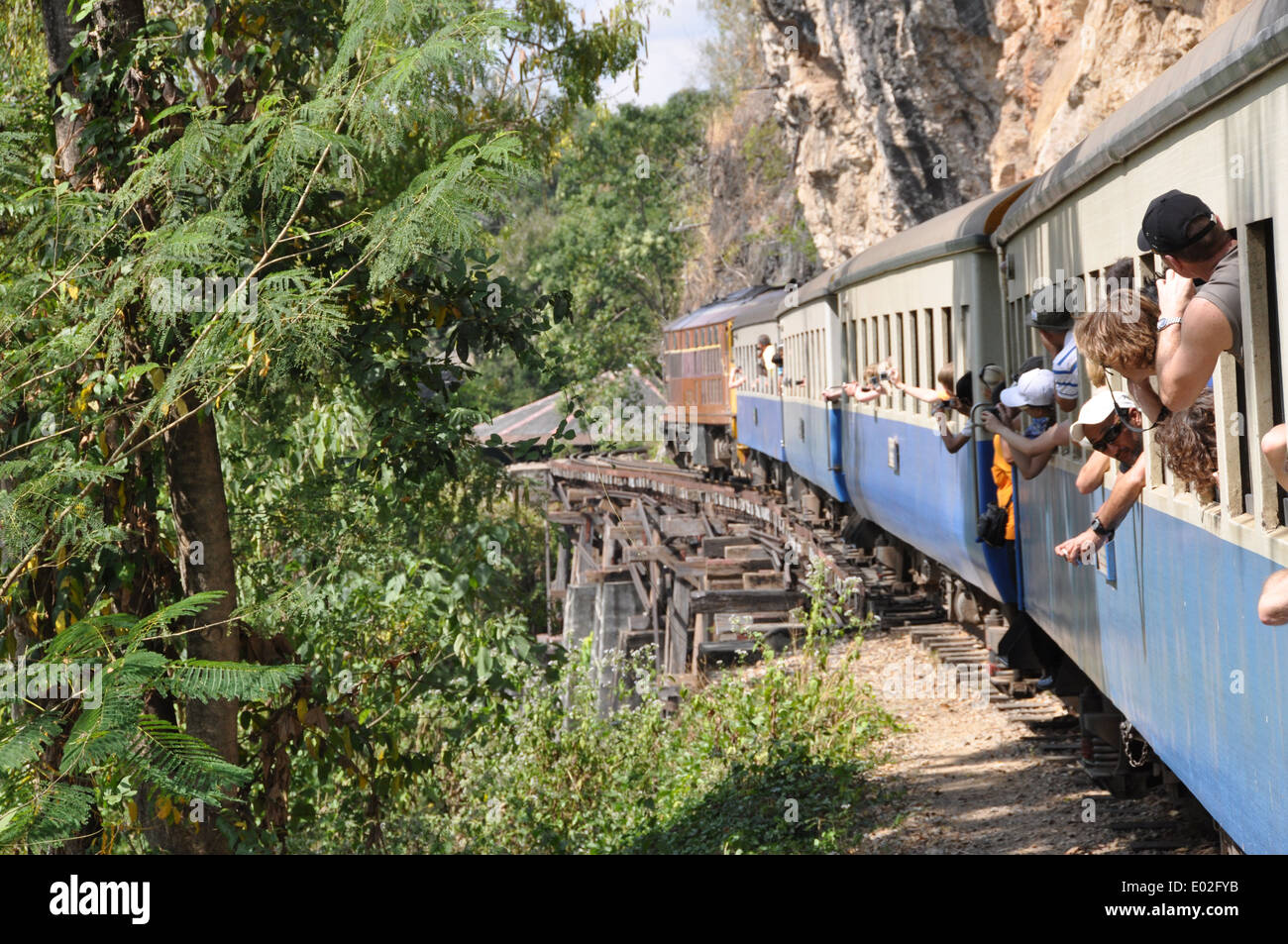 Les touristes se penchant par la fenêtre d'un train sur la Thai - Birmanie chemin de fer, la Thaïlande. Banque D'Images