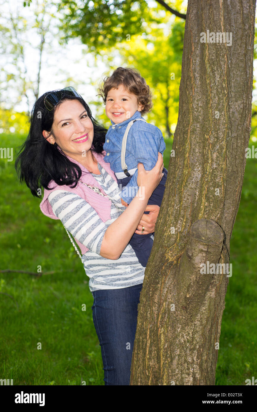 Maman et enfant garçon se cacher derrière arbre et s'amuser ensemble Banque D'Images