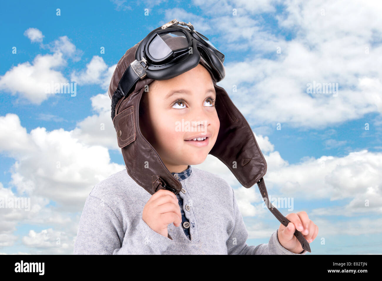 Jeune garçon avec casque pilote isolés contre le ciel Banque D'Images
