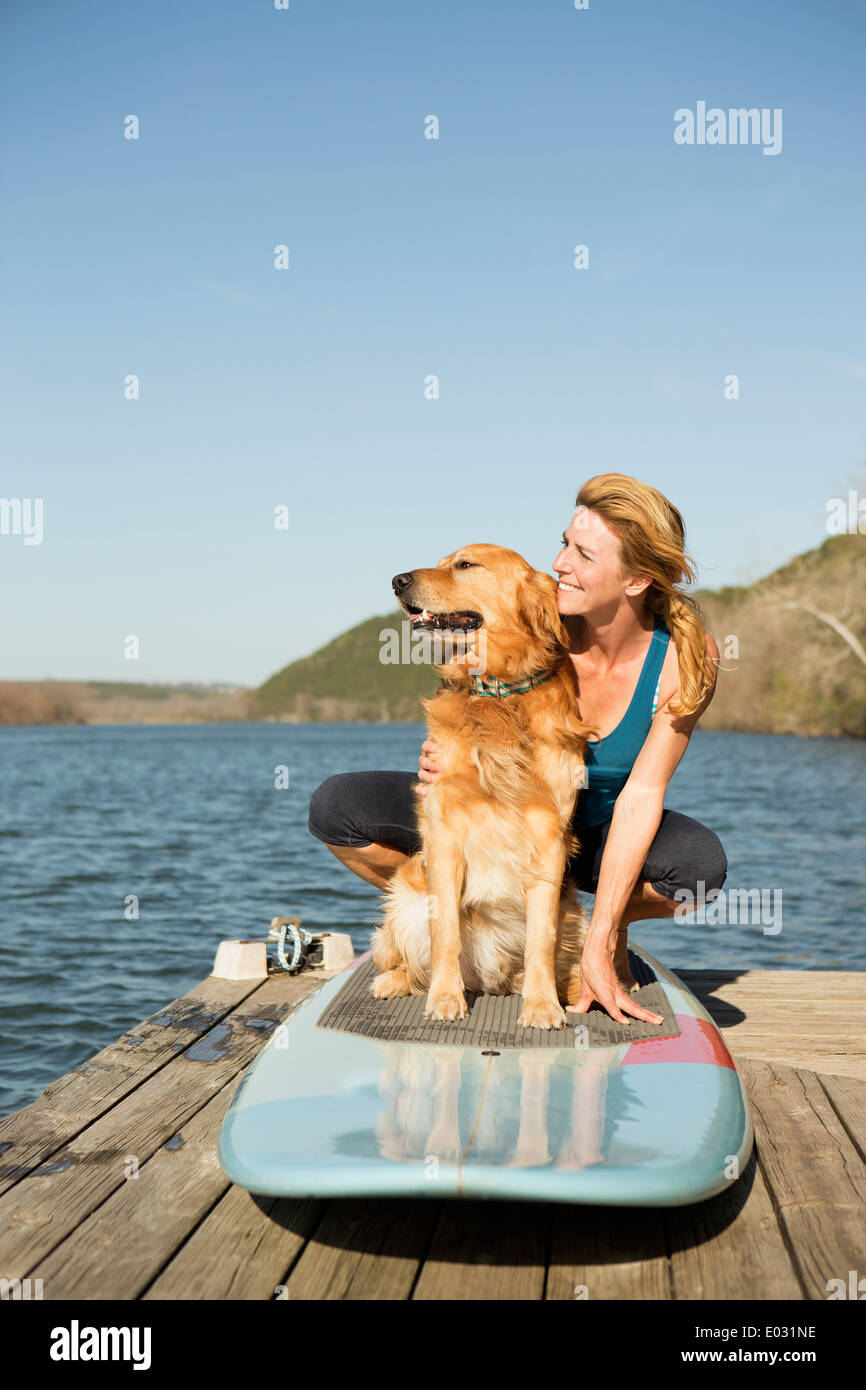 Une femme et un retriever chien sur un paddleboard sur la jetée. Banque D'Images