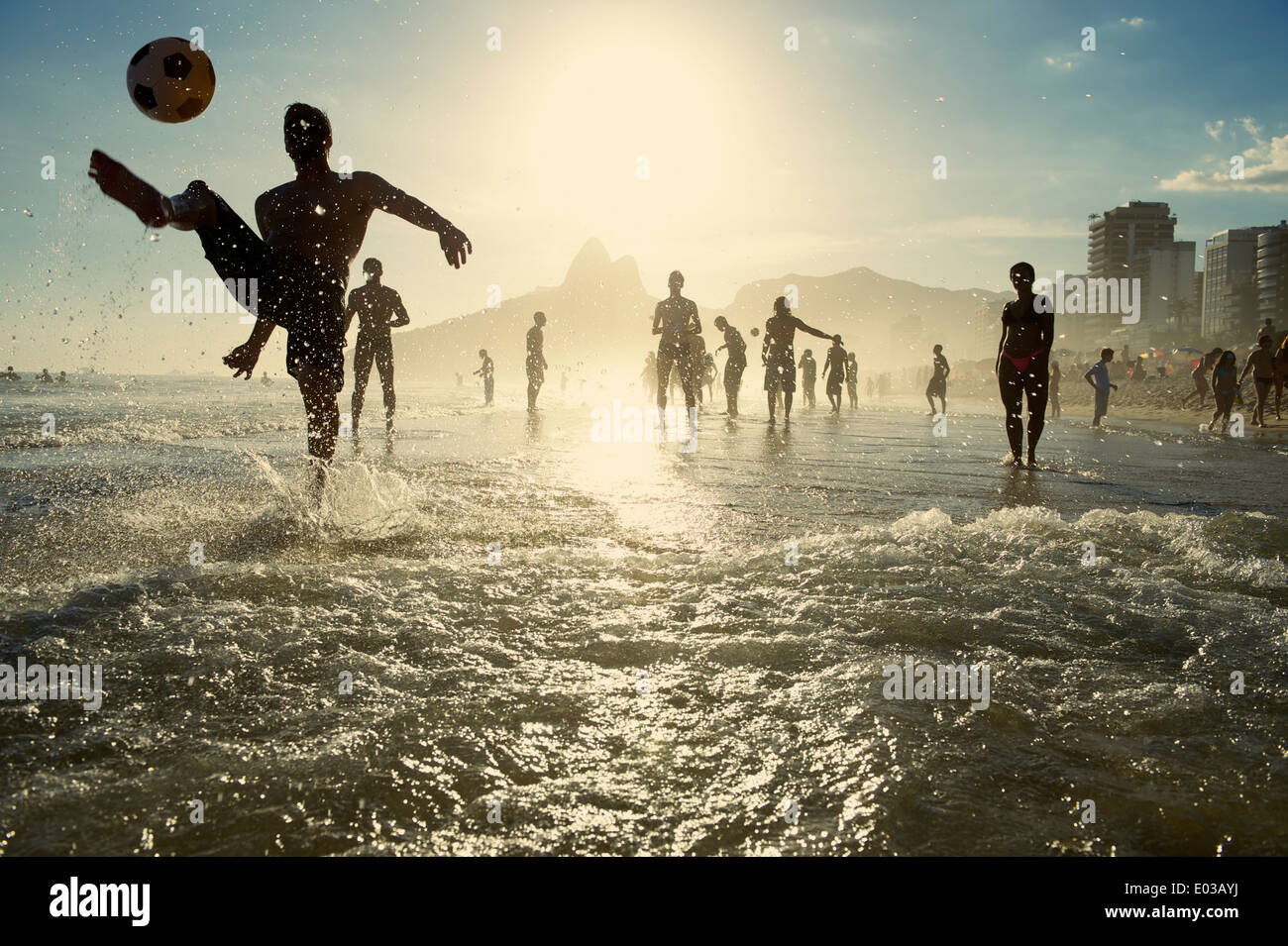 Carioca brésiliens jouant altinho beach football en silhouettes coups de ballons de foot dans les vagues de la plage d'Ipanema Rio de Janeiro Banque D'Images