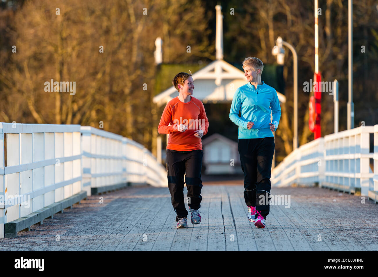 Deux femmes ensemble jogging le long du pont au lever du soleil Banque D'Images