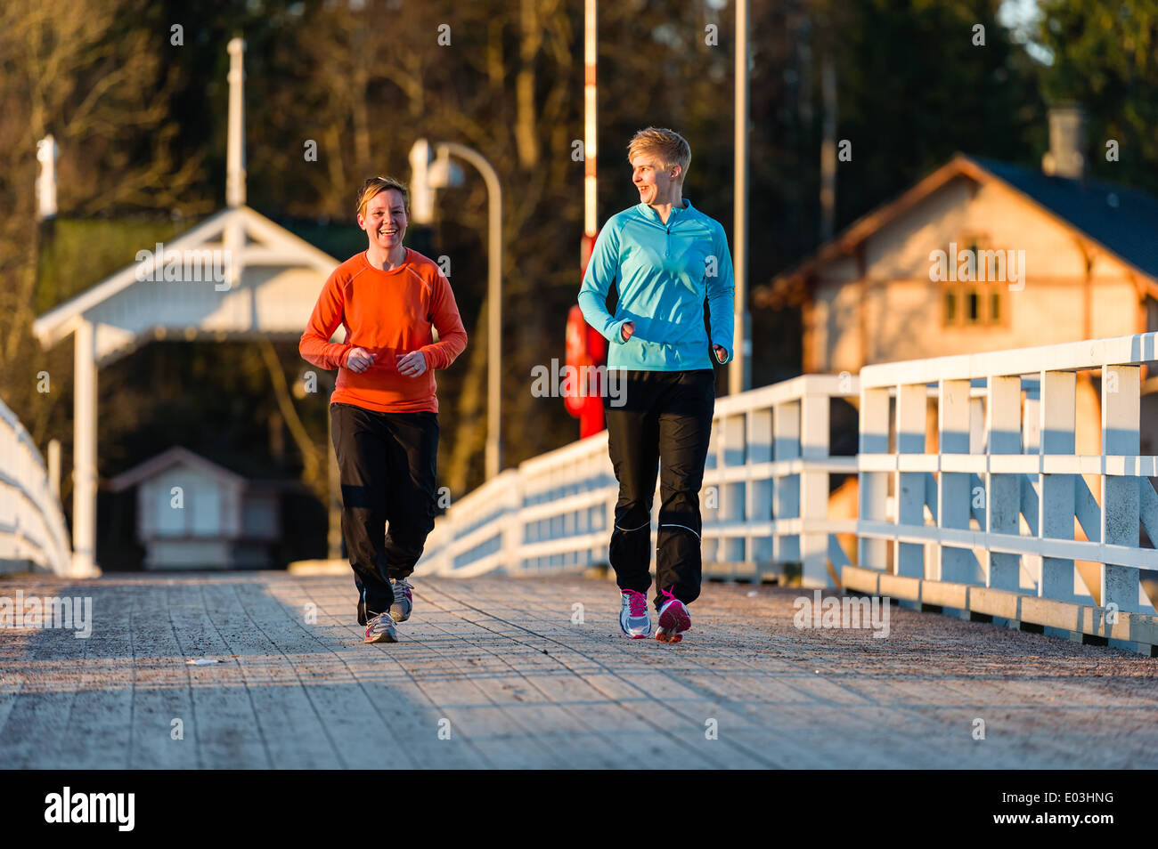Deux femmes ensemble jogging le long du pont au lever du soleil Banque D'Images