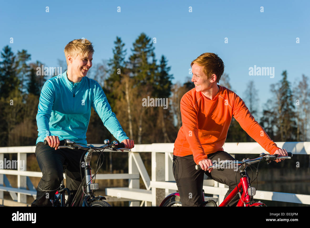 Deux femmes ensemble à vélo le long du pont au lever du soleil Banque D'Images