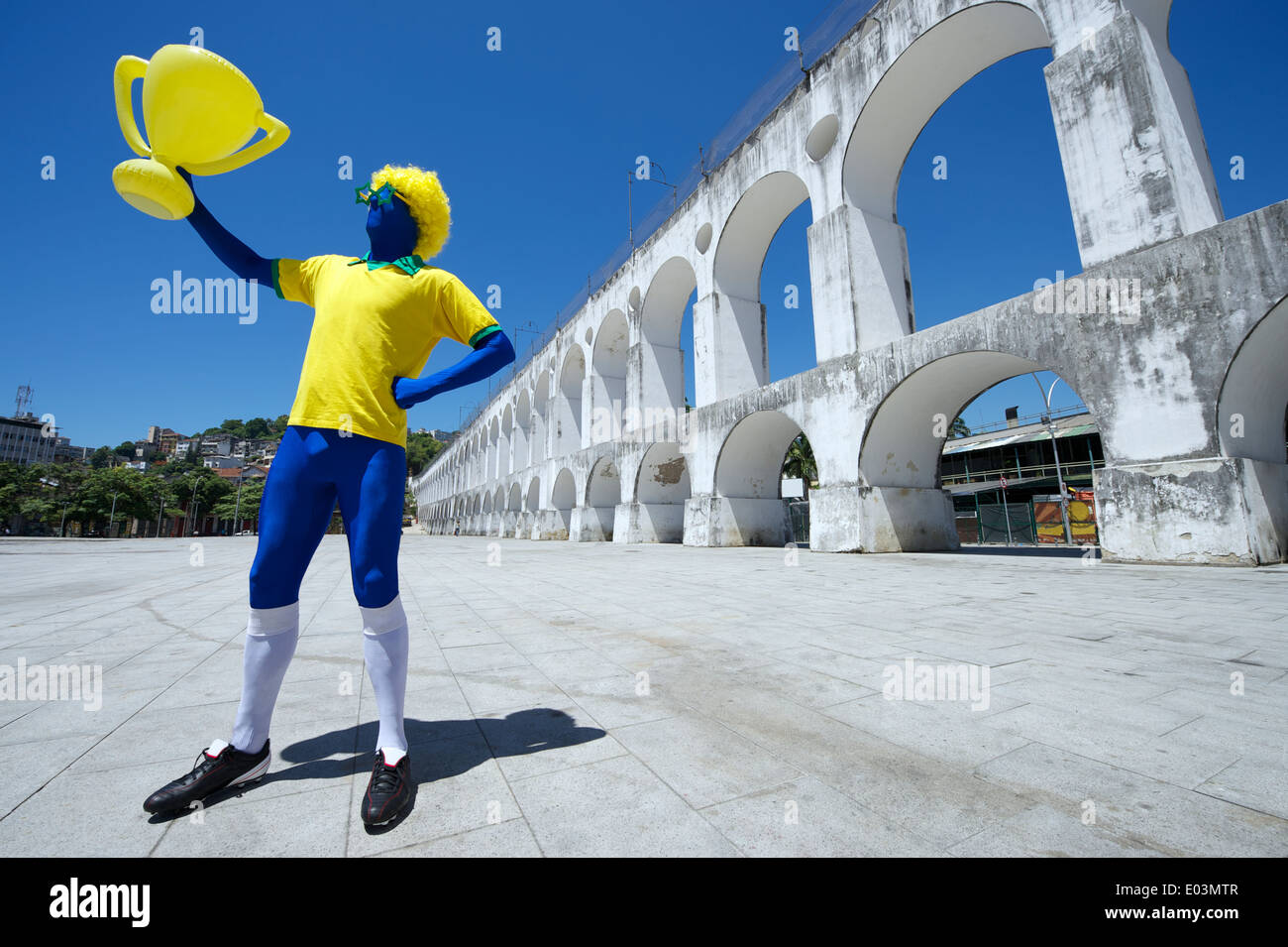 Fier blue joueur de football brésilien, holding trophy célébrer dans les couleurs de l'équipe du Brésil à Rio de Janeiro Banque D'Images