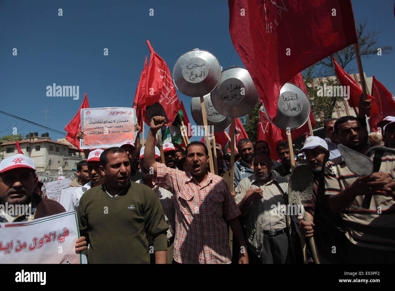 Gaza, la Palestine. 01 mai, 2014. Travaux palestinienne slogans chant comme d'autres l'attente lors d'un des bols mars pour la Journée internationale du travail dans la ville de Gaza, le Jeudi, Mai 1, 2014. L'arabe se lit, ''Le bol de la faim, la pauvreté et la famine, où est la conscience, '' Selon le Bureau des Nations Unies pour la coordination des affaires humanitaires, le taux de chômage dans la bande de Gaza est l'un des plus élevés au monde. Credit : ZUMA Press, Inc./Alamy Live News Banque D'Images