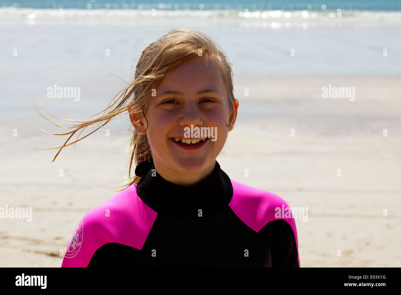 Douze ans fille blonde on beach in wetsuit smiling Banque D'Images