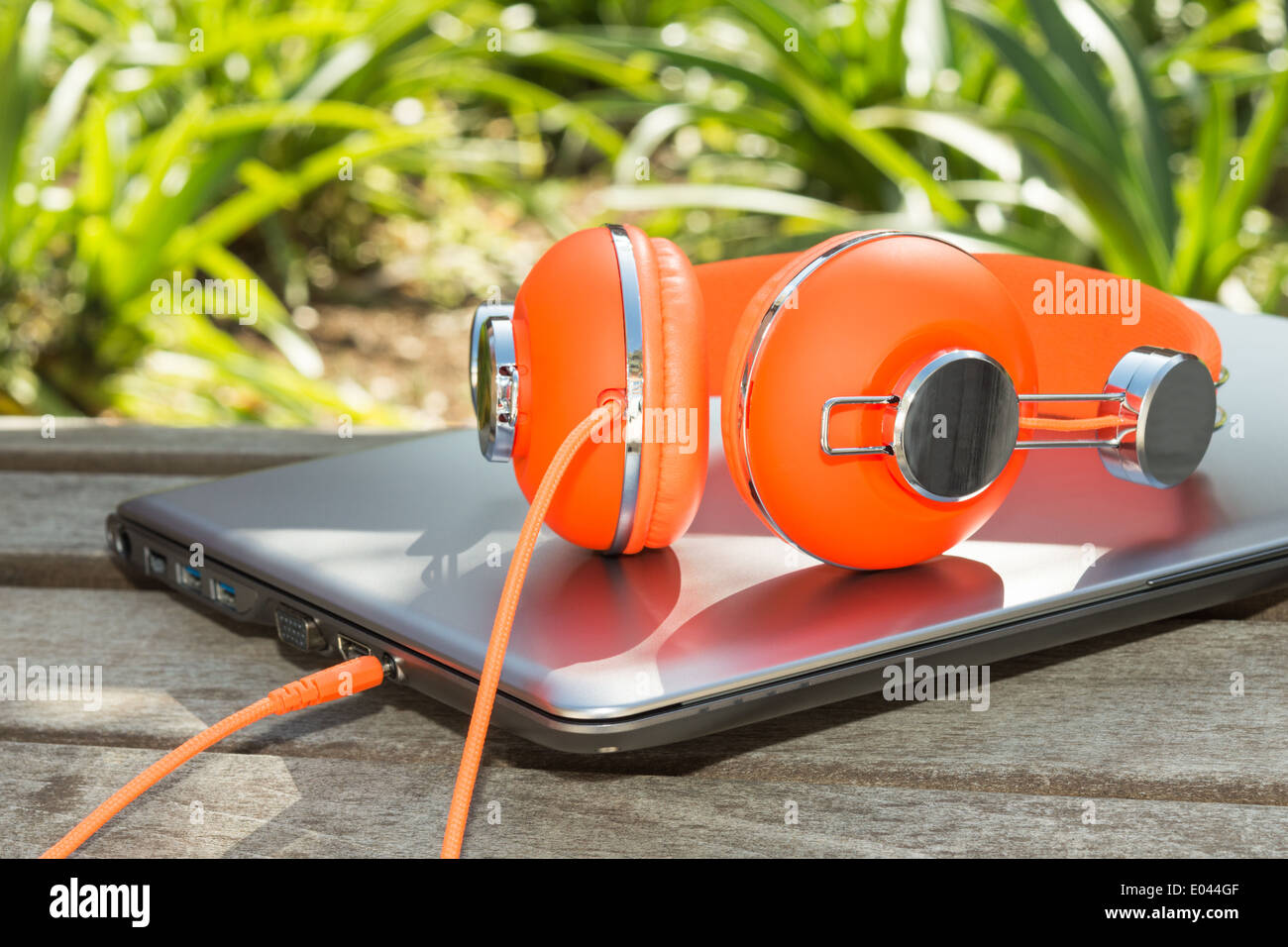 De couleur orange vif et casque ordinateur mobile sur le banc dans le parc Banque D'Images