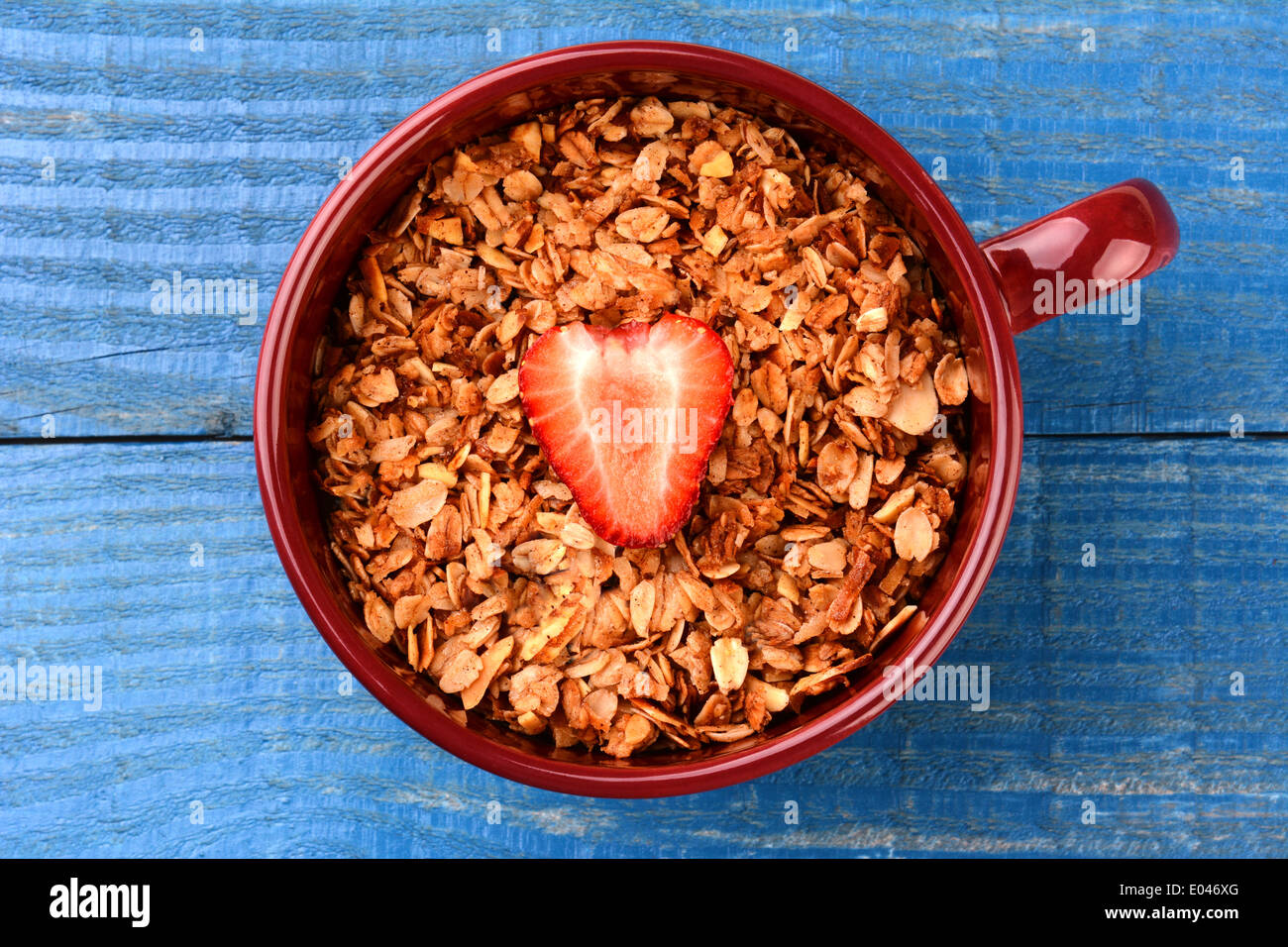 High angle shot d'une grande tasse remplie de céréales à grains entiers sains avec une seule fraise en tranches au milieu. Banque D'Images