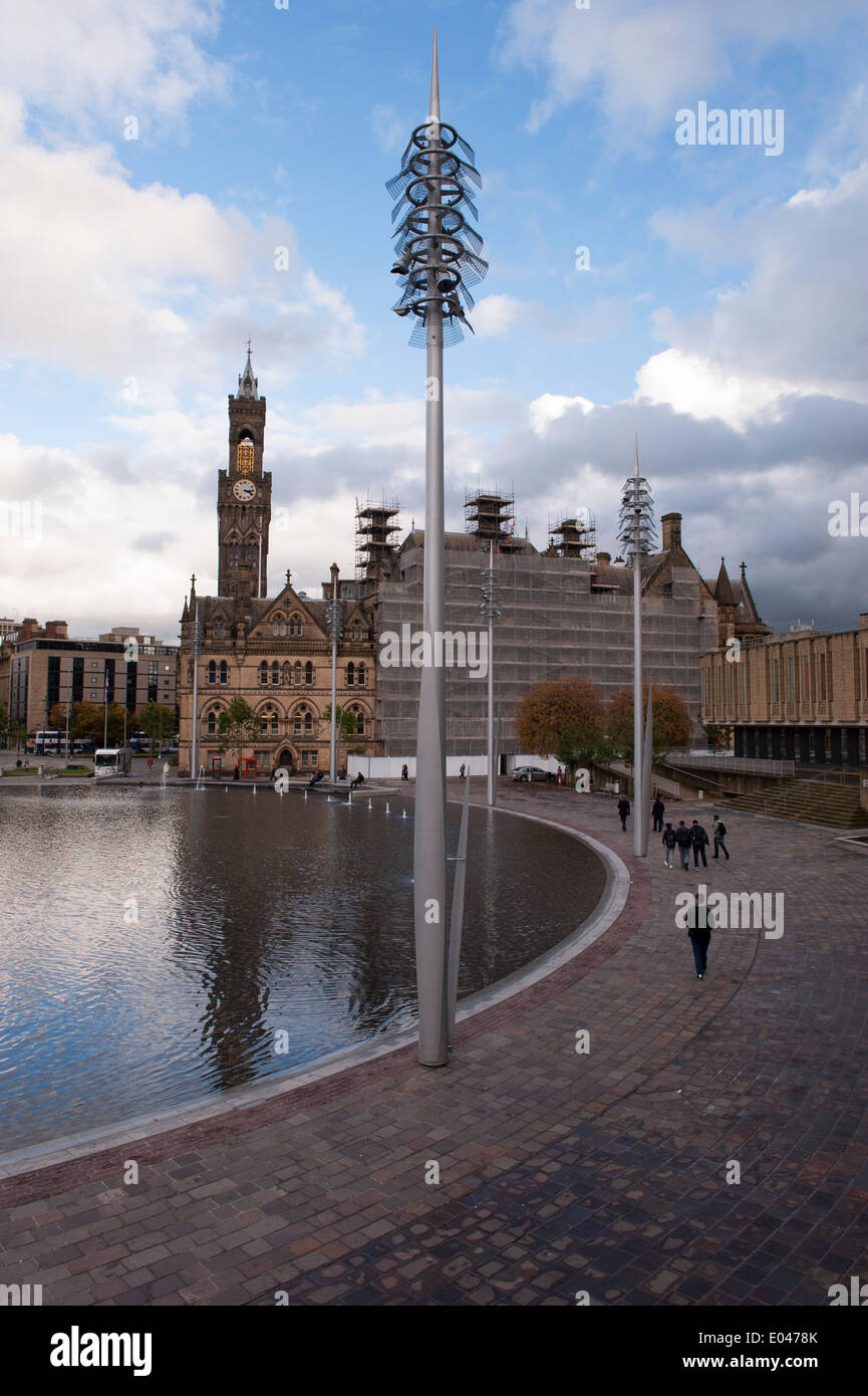 Sous le ciel bleu, les gens marchent à Bradford City Park au grand miroir courbe extérieure, l'hôtel de ville et sa tour impressionnante au-delà - West Yorkshire, Angleterre, Royaume-Uni. Banque D'Images