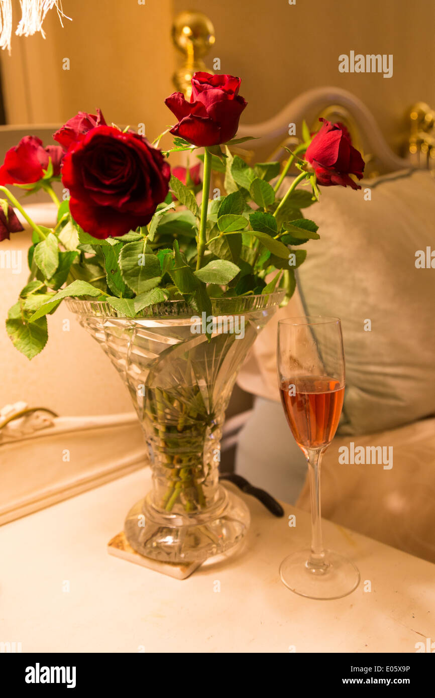 Roses et un verre de vin d'attente à la table de chevet d'un hôtel romantique au bord du lac de Windermere. Banque D'Images