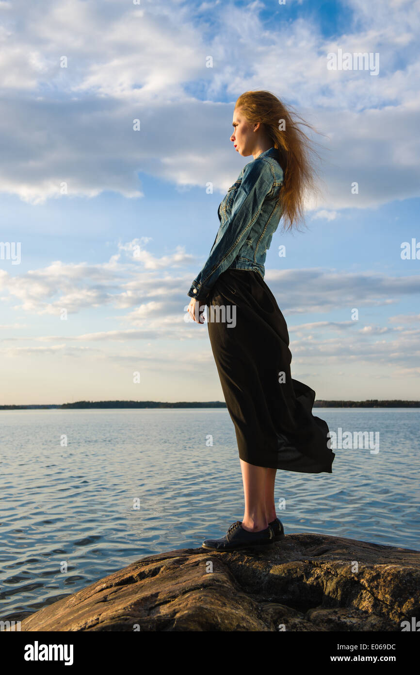 Belle jeune femme regarde l'horizon à terre - le vent souffle et ciel  nuageux Photo Stock - Alamy
