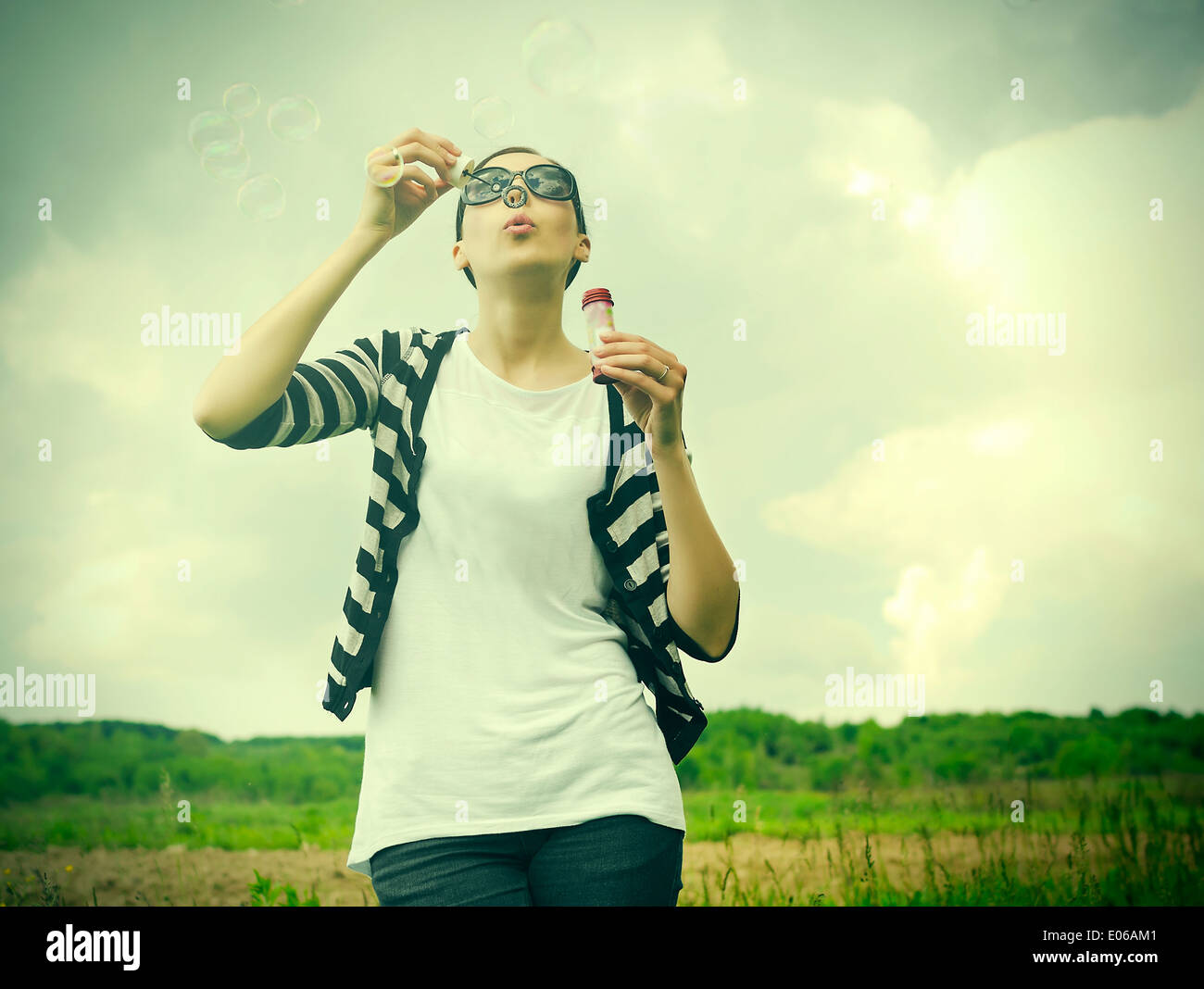 Jeune fille soufflant des bulles de savon dans park Banque D'Images