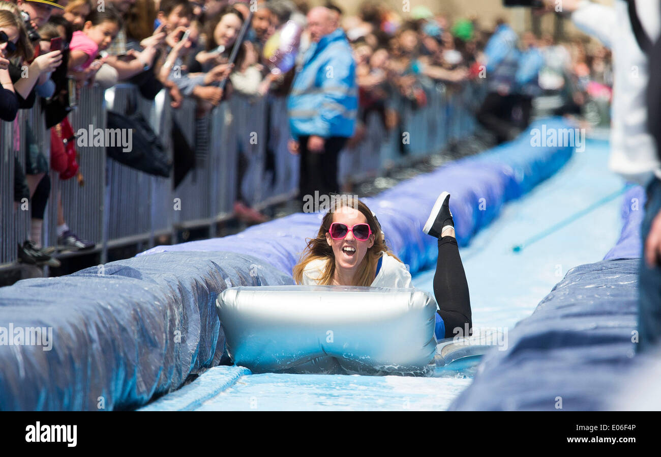 Bristol, Royaume-Uni. 04 mai, 2014. Les gens vers le bas de la vitesse d'un toboggan de 90m érigée sur la rue Park à Bristol. Luke Jerram artiste a organisé l'événement où 300 personnes va dévaler des feuilles de plastique trempé dans du liquide vaisselle et bordée de 400 balles de foin. 4 mai 2014 Crédit : Adam Gasson/Alamy Live News Banque D'Images