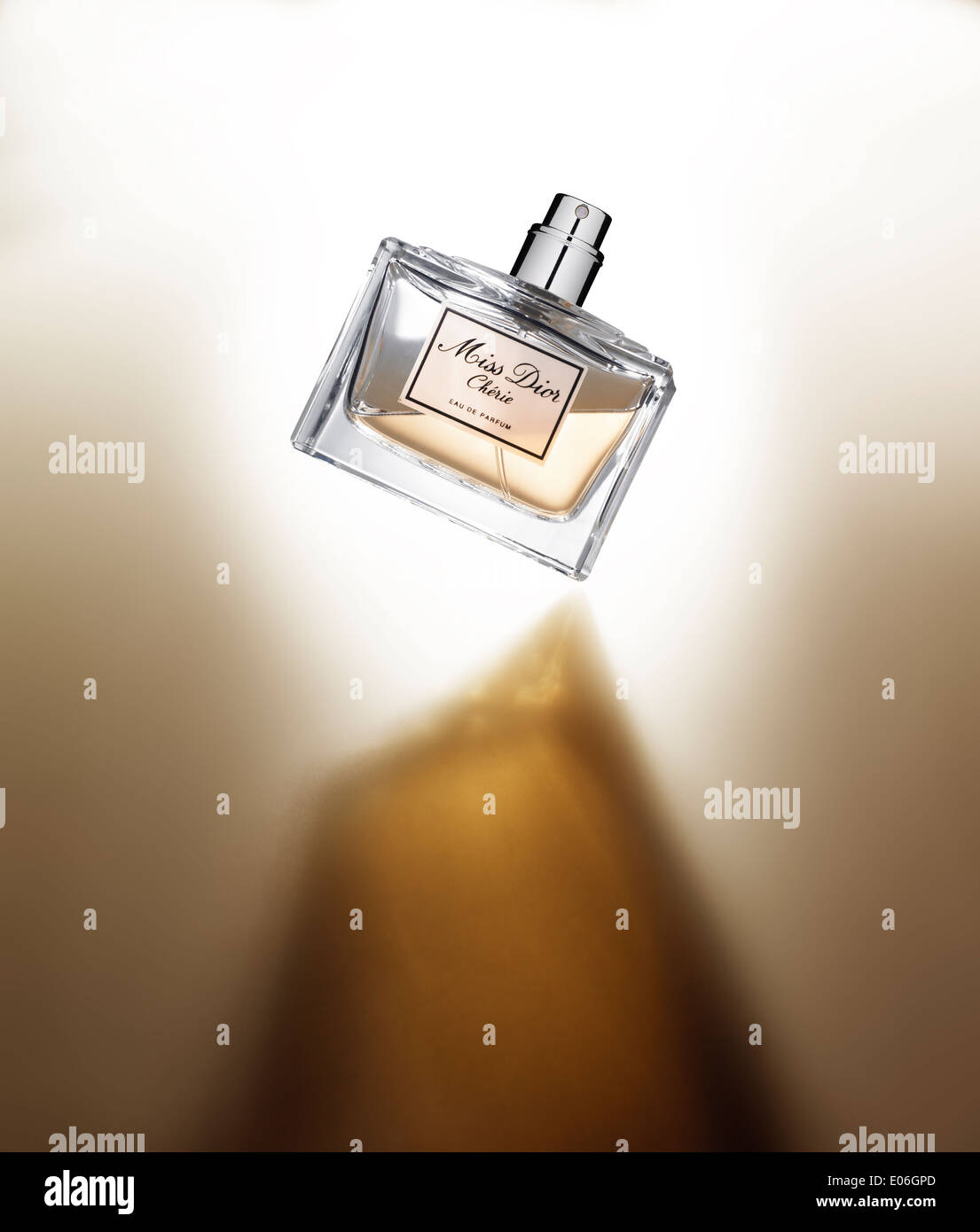 Un flacon de parfum en équilibre sur une surface blanche avec une ombre Banque D'Images