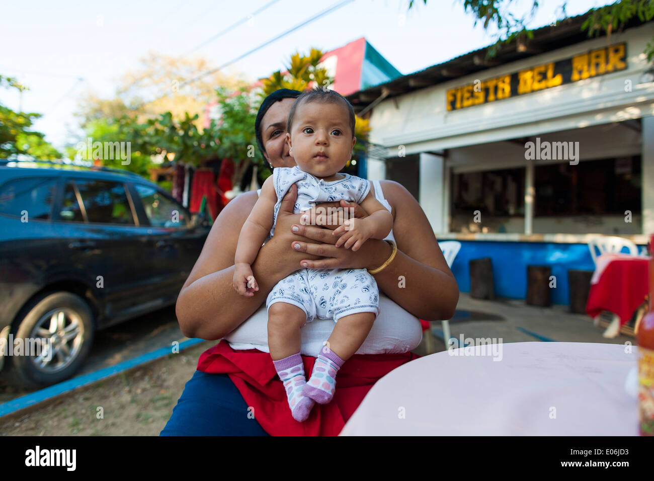 Une femme du Costa Rica est titulaire d'une fille de bébé dans ses mains à Tamarindo Costa Rica. Les enfants sont au cœur de la culture sociale du Costa Rica Banque D'Images