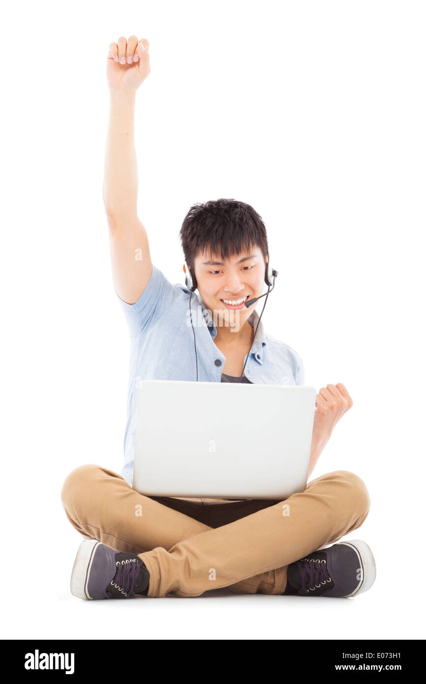Succès de jeune homme assis sur le sol et en utilisant un ordinateur portable Banque D'Images