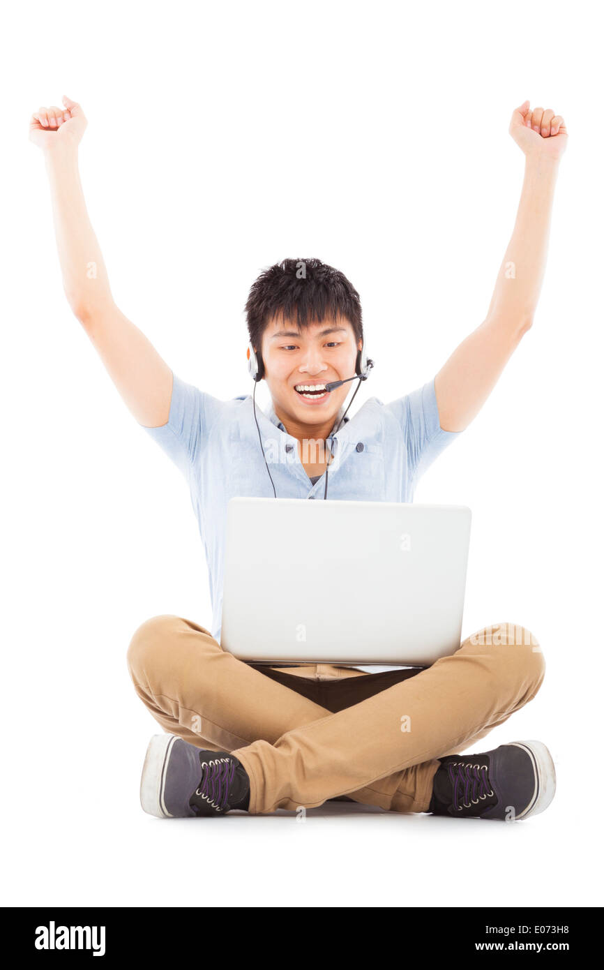 Succès de jeune homme assis sur le plancher et d'élever les mains Banque D'Images