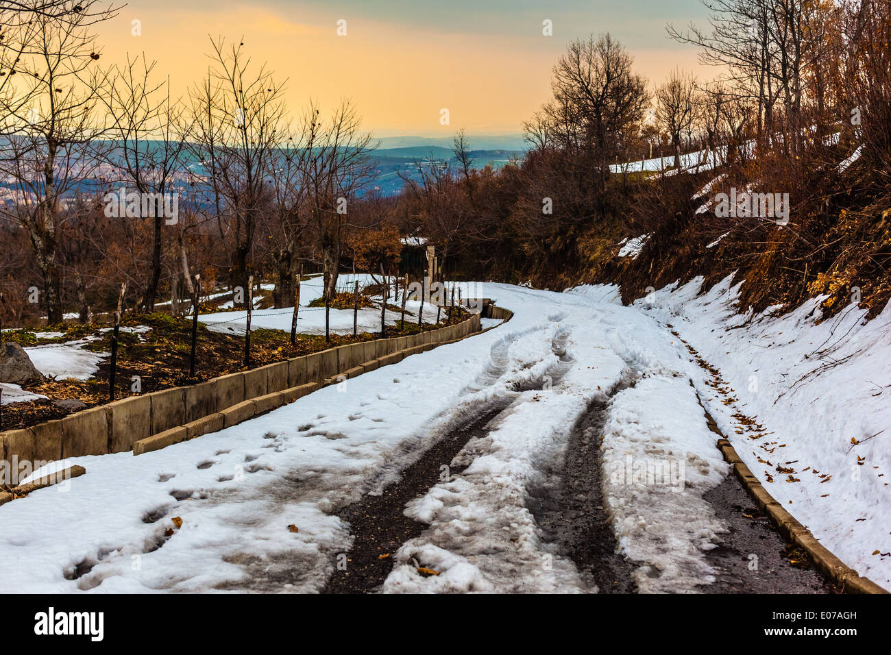 Une route enneigée dans les montagnes avec des arbres et ciel bleu Banque D'Images